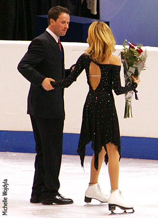 Tanith steadies Igor as he steps onto the ice in dress shoes