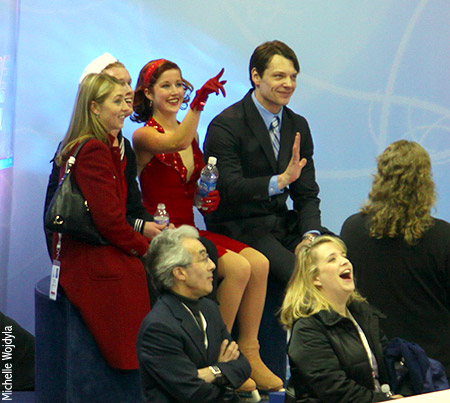 Emily Samuelson points to the Jumbotron, where they are showing a very old photo of her and Evan Bates