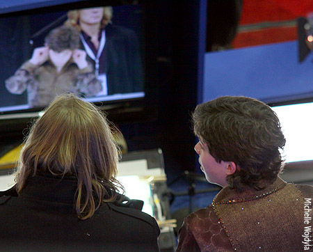 Keegan Messing and coach Ralph Burghart watch the replay of Keegan covering his ears so he couldn't hear the scores of the skater before him