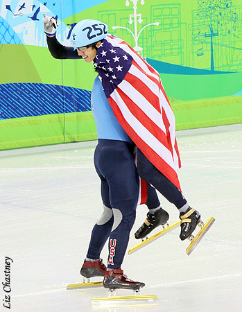 Apolo Ohno celebrates with a flag-wrapped JR Celski
